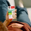 Mann hält sich den Bauch und hält Doppelherz Bei Reizdarm in der anderen Hand